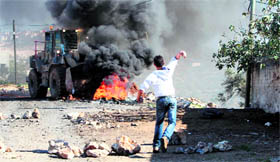 A Palestinian protester throws a stone towards an Israeli bulldozer in the West Bank village of Kafr Qaddum, near Nablus, on Friday.