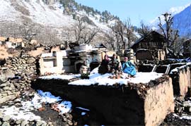 Ghulam Nabi Sheikh along with his family members sits in front of his gutted house at Frislan village in Pahalgam.