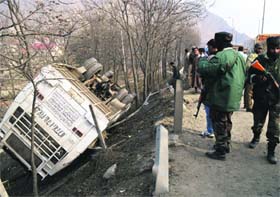 Security personnel inspect a damaged passenger bus which fell into a gorge near Panthachowk on Sunday. Fifteen persons were injured in the accident.