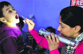 A dental surgeon examines a child during a free medical check-up camp orgnised by the Ek Noor Charitable Educational and Welfare Trust at Kiddies Paradise School.