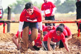 Participants run through a mud pit