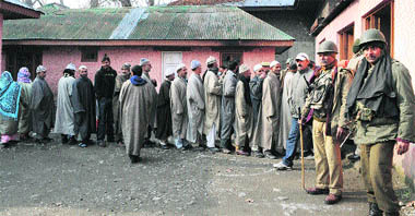 Security personnel stand guard as panches and sarpanches queue up to cast their votes for the Legislative Council elections in Ganderbal district in central Kashmir on Monday. 