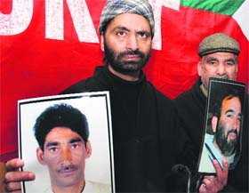 JKLF chairman Yasin Malik shows photograph of Sheikh Nazir Ahmad and Showkat Ahmad Khan in Srinagar on Monday.