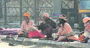 Shelterless people sit on a road berm in Jalandhar.