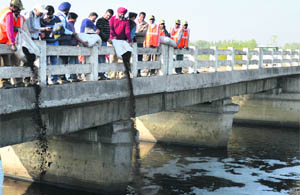 Officials release microbes into the Budha Nullah in Ludhiana on Tuesday. 