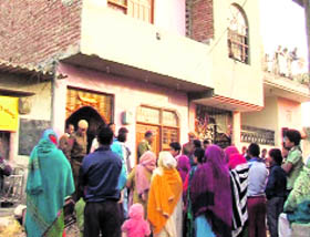 Neighbours gather outside the deceased's house.