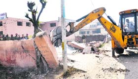 MC staff pull down a wall near Kuki Dhab in Jalandhar on Wednesday