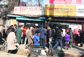 People wait for their turn to get their cooking gas papers verified in Srinagar