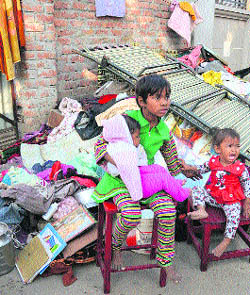 Children sit with their belongings after the demolition drive.