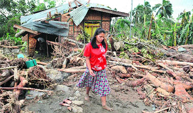 A woman inspects her damaged house in Andap village, Compostela Valley province, on Wednesday. 