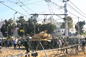 Army soldiers set up barbed wire barricades and deploy tanks outside the Presidential palace in Cairo on Thursday
