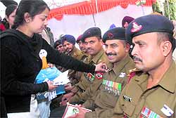 Students paste stickers on the uniform of soldiers at Punjab State War Memorial on the occasion of Armed Forces Flag Day in Jalandhar on Friday
