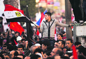 A demonstrator waves the national flag as thousands gather near the Presidential Palace in Cairo on Friday. 