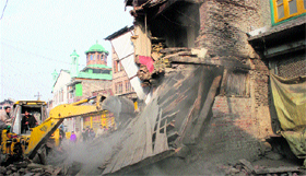 A JCB pulls down a house during a demolition drive at Khankahi Moulla in downtown Srinagar on Saturday.
