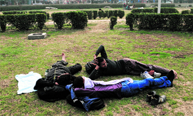 Youths take a nap at Pratap Park in Srinagar on Saturday.