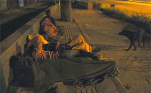 Shelterless people sleep on footpath near ITO in New Delhi on Sunday.