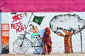 A beggar stands in front of a mural on the streets of Rawalpindi in Pakistan on Sunday