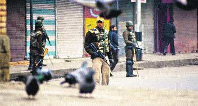 Policemen stand guard near closed shops during a strike called by the Jammu Kashmir Liberation Front to mark the International Human Rights Day in Srinagar on Monday.