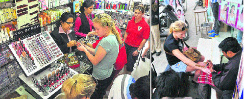 English kabaddi players shop at a market; and (right) another player gets henna applied on her hand in Ludhiana on Monday.