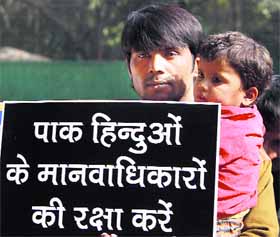 A Pakistani Hindu with his child holds a placard seeking more rights for refugees during a protest outside the UN office in New Delhi on Monday.