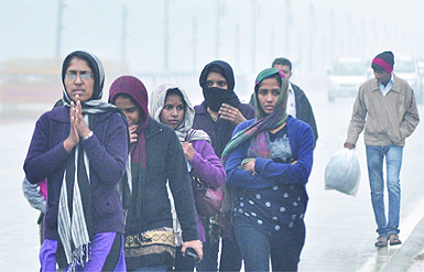 Braving the cold: Girls cover themselves with scarves in a chilly day as Delhi received scattered showers on Tuesday. 