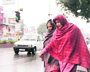 Women face a tough time during rain in Dehradun on Tuesday. 