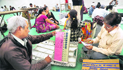 Election officials examine an electronic voting machine at a distribution  centre at Dholka near Ahmedabad on Wednesday.  PTI