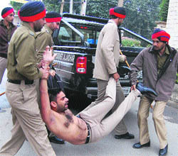 Policemen bundle a protester into a vehicle when he was heading towards the house of the state Local Bodies Ministers in Jalandhar on Thursday. 