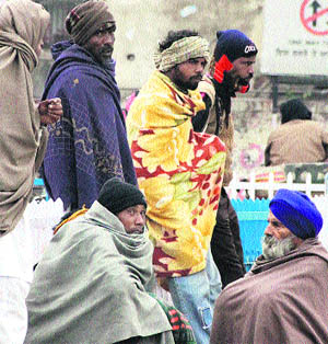 Passengars await their train under shivering conditions at Jalandhar city Railways Station on Thursday. 
