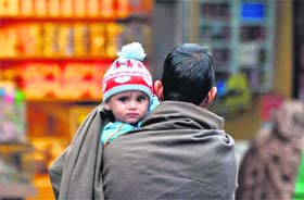 A man protects his child from the chill in Jammu on Thursday