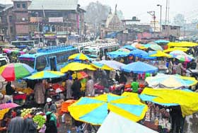 People buy vegetables at a market on a rainy day in Srinagar