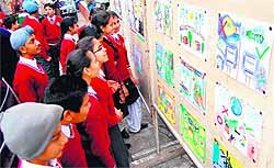 Students take a look at the posters during an exhibition to mark National Energy Conservation Day in Amritsar on Friday
