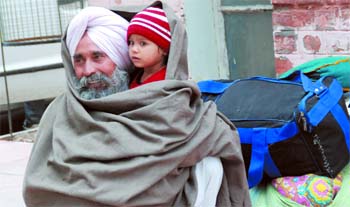 A man wraps a shawl around himself and his grandchild in an attempt to keep warm. After rainfall on Thursday, sky remained cloudy on Friday as well. The sky is expected to clear within a day or two.