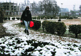 A youth crosses a park in Srinagar. The city received light snowfall on Thursday night.