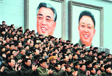 North Koreans applaud in front of portraits of founder Kim Il-sung (L) and late leader Kim Jong-Il at a rally in Pyongyang on Friday.