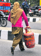 A woman carries a LPG cylinder.