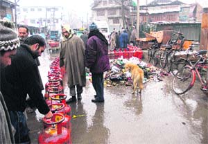 People wait for their turn to get LPG cylinders in Srinagar on Sunday.