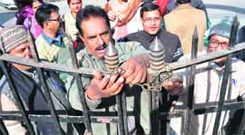Striking state government employees lock the gate of the office of the Director of Education against reservations in promotions in Dehradun on Monday.