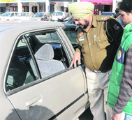 A policeman inspects the car from which a bag containing cash was stolen at Sector 20 in Chandigarh