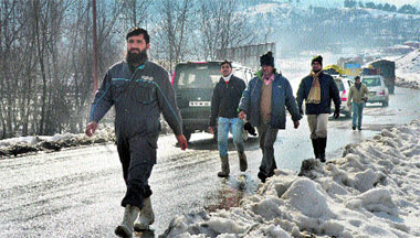 People walk on the road at Qazigund in Anantnag district on Tuesday as slippery conditions continue to trigger traffic jams.