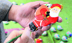An artisan gives finishing touches to a creation depicting Santa Claus in Srinagar. 