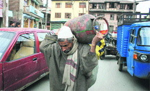 An elderly man carries an LPG cylinder on his shoulders in Srinagar. 
