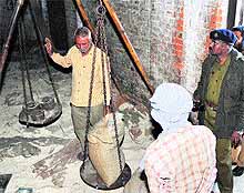 A police officer inspects a foodgrain bag during a raid on a CAPD store in Warehouse area of Jammu on Wednesday