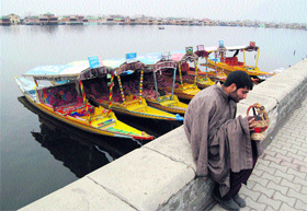 A shikara owner keeps warm with a kangri (fire pot) while waiting for prospective customers on the banks of the Dal Lake in Srinagar on Thursday.
