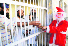 A student, dressed up as Santa Claus, offers chocolates to prisoners at Kotbhalwal Central Jail ahead of Christmas celebrations in Jammu on Wednesday.