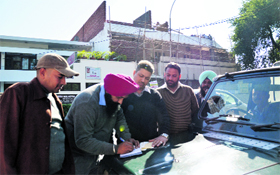 MC officials fill composition fee forms near an under-construction building in Ludhiana on Thursday.