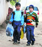 Students of Government Primary School, Mauli Baidwan, carry uniforms in polybags on Friday. 