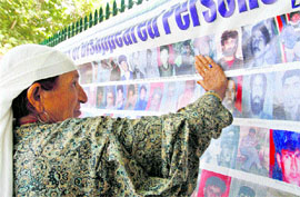 A woman looks at a poster of disappeared persons in the Kashmir valley.