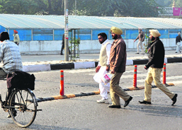 Policemen, escorting an undertrial, cross the road on which an underpass has been built, in Ludhiana on Saturday.