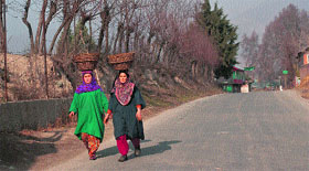 Women carry baskets on their heads as they walk on a road in central Kashmirs Ganderbal district.